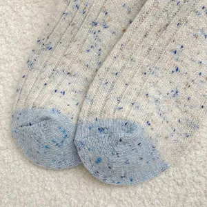 Close-up detail of thick wool blend cable knit slouch socks with cozy speckled texture.