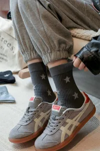 Detail shot of grey ribbed socks with star patterns worn with sneakers for a stylish look.
