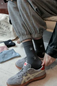 Grey mid-calf socks featuring embroidered star patterns and ribbed cuffs, detailed shot.