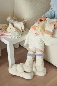 Close-up detail of cozy fuzzy polka dot mid-tube wool socks with fluffy plush trim design.
