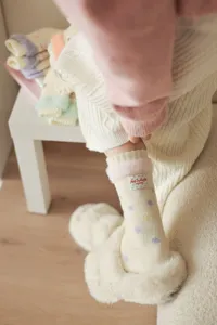 Close-up detail of women's thick dot yarn slouch socks with cute label and cozy wool blend.