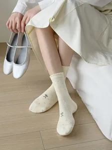 Close-up detail of cream stacking socks with cute bow embroidery and delicate lace ruffle trim.