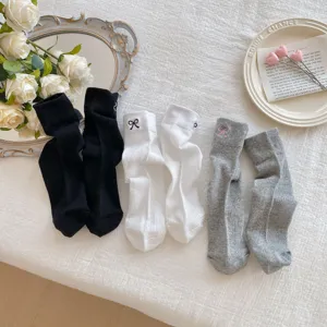 Detailed view of women's stackable socks featuring cute bow embroidery in black, white, and grey.