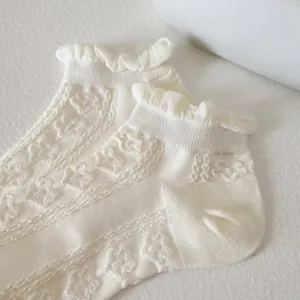White lace ruffle ankle socks, delicate floral knit texture close up detail view.