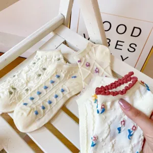 Detail view of white women lace socks featuring cute floral embroidery and sweet heart patterns.