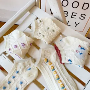 Detail view of cute Japanese style white lace socks with floral and heart embroidery for women.