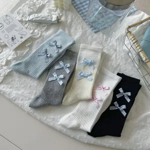 Detailed flat-lay view of cozy knit socks featuring cute plaid bows in various lovely colors.