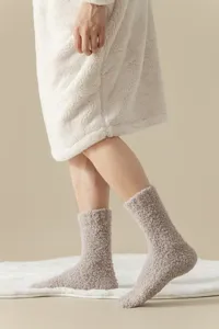 Close-up detail of soft fuzzy warm coral fleece socks for cozy winter indoor home sleep wear.