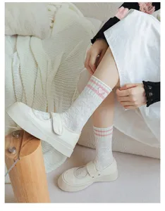 Detail shot of sweet white mid-tube socks featuring pink stripes and cute heart embroidery.