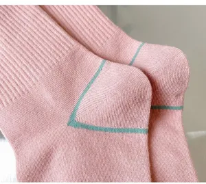 Close-up detail shot of pink knit mid-tube socks featuring stylish green heel stitching.