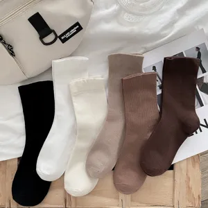 Detailed shot of solid color ribbed mid-calf socks in assorted neutral shades, soft fabric.