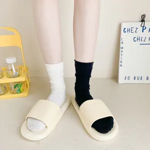 Detail view of women's mid-tube socks paired with casual minimalist slide sandals indoors.