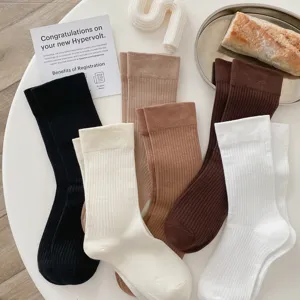 Detailed flat lay of soft ribbed mid-calf socks in assorted neutral colors on a white table.