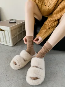 Close-up detail of women's soft ribbed mid-tube socks paired with cozy fluffy slippers.
