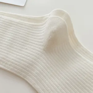 Close-up detail shot of white ribbed knit socks, showing soft texture and fine vertical stripes.