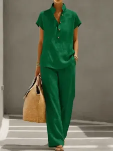 Detailed view of a green linen short sleeve top and matching trousers set worn outdoors.