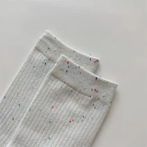 Primo piano di calzette bianche da donna con filato maculato colorato, cotone morbido.
