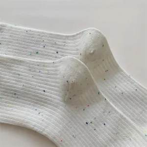 Primo piano dettagliato di calzini morbidi bianchi da donna con filato maculato colorato.