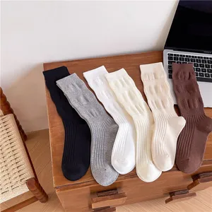 Dettaglio di calzini slouch da donna in maglia a coste posati ordinatamente sopra un tavolo di legno.