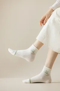 Close-up detail of white Japanese cute style short socks with green stripe and smile pattern.