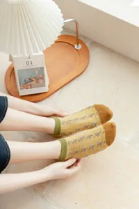 Detailed view of cute Japanese style women socks with yellow pattern and green cuffs.