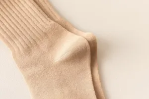 Close-up detail of soft knit ribbed socks in a neutral cream tone, showing fine texture.