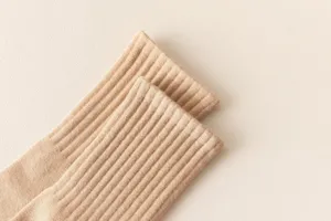 Close-up detail of cream vertical striped mid-tube knit socks, soft texture and cozy wear.