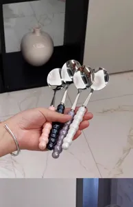Stainless steel soup spoon detail, ceramic beaded handle, elegant kitchen tableware display.