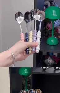 Stainless steel spoon with colorful ceramic beaded handle, detail view showing grip and design.