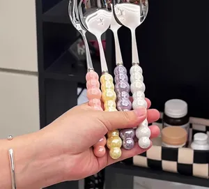 Close-up detail of stainless steel soup spoons featuring colorful ceramic beaded handles.