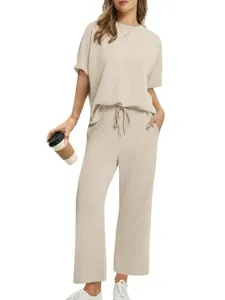 Detailed shot of casual solid beige short-sleeve top and loose trousers set worn by model.