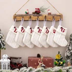 White knitted Christmas stockings set with red embroidered letters and cute festive holiday decor.