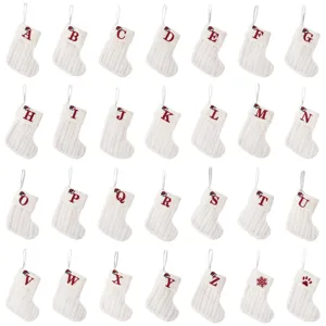 White knitted Christmas stockings with red embroidered letters, festive gift bags for holiday.