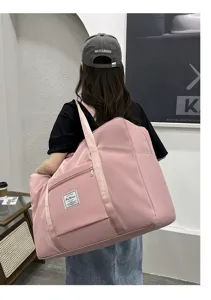 Pink large travel duffel bag detail, showing durable waterproof fabric and front zipper pocket.