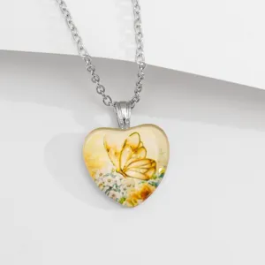 Close-up van de hartvormige glazen hanger halsketting met vlinder- en bloemendetails.