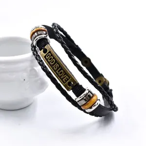 Primer plano de pulsera de cuero trenzado multicapa vintage con placa metálica inspiradora.
