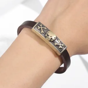 Primo piano dettagliato di un bracciale in pelle punk vintage con placca teschio in bronzo.