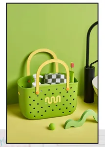Vue détaillée du panier de douche en plastique vert avec poignées jaunes et trous pour dortoir.