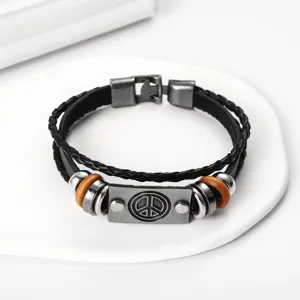Detailed closeup of retro multi-layer braided leather bracelet with peace symbol metal plaque.