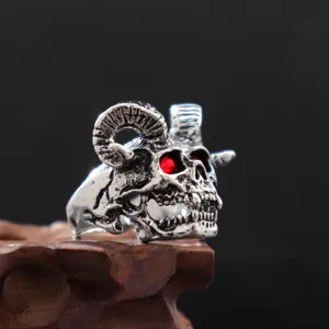 Close-up detail van gothische punk ram schedel ring met rode zirkonia ogen en zilveren afwerking.