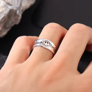 Nahaufnahme Detail eines silbernen unregelmäßigen offenen Rings mit graviertem Gesicht.