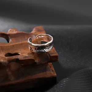 Nahaufnahme des unregelmäßigen Silberrings mit gravierten Keep- und Smiley-Gesichtsdetails.