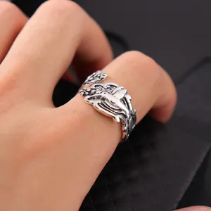 Primo piano dettaglio dell'anello colibrì regolabile in argento vintage con rilievo floreale.