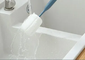 Vue détaillée du nettoyeur de tasse en éponge à long manche lavé dans un évier de cuisine.