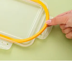Clear plastic lunch box detail showing removable yellow silicone sealing ring for food storage.