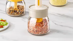Gros plan du pot à épices en verre avec couvercle cuillère intégré et sel grossier.