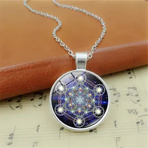 Detailaufnahme einer Halskette mit Glascabochon Anhänger und heiligem Geometrie Motiv auf Noten.