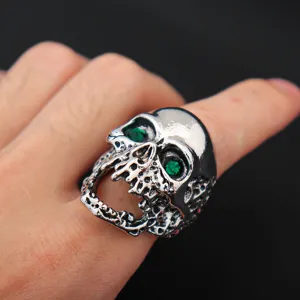 Close-up detail of punk style alloy oversized skull ring featuring vibrant green zircon stones.