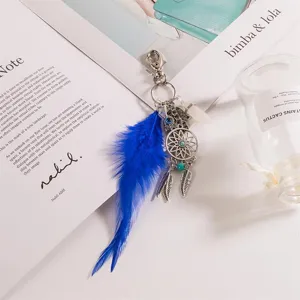 Λεπτομερής εικόνα boho μπρελόκ φτερού με τουρκουάζ πέτρα και μεταλλικό φυλαχτό χεριού.