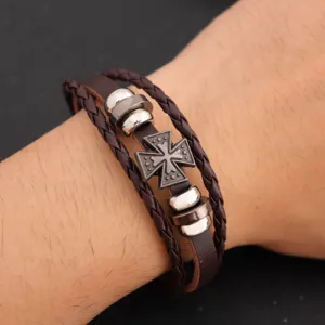 Nahaufnahme des Retro geflochtenen Lederarmbands mit Metallkreuzanhänger am Handgelenk.